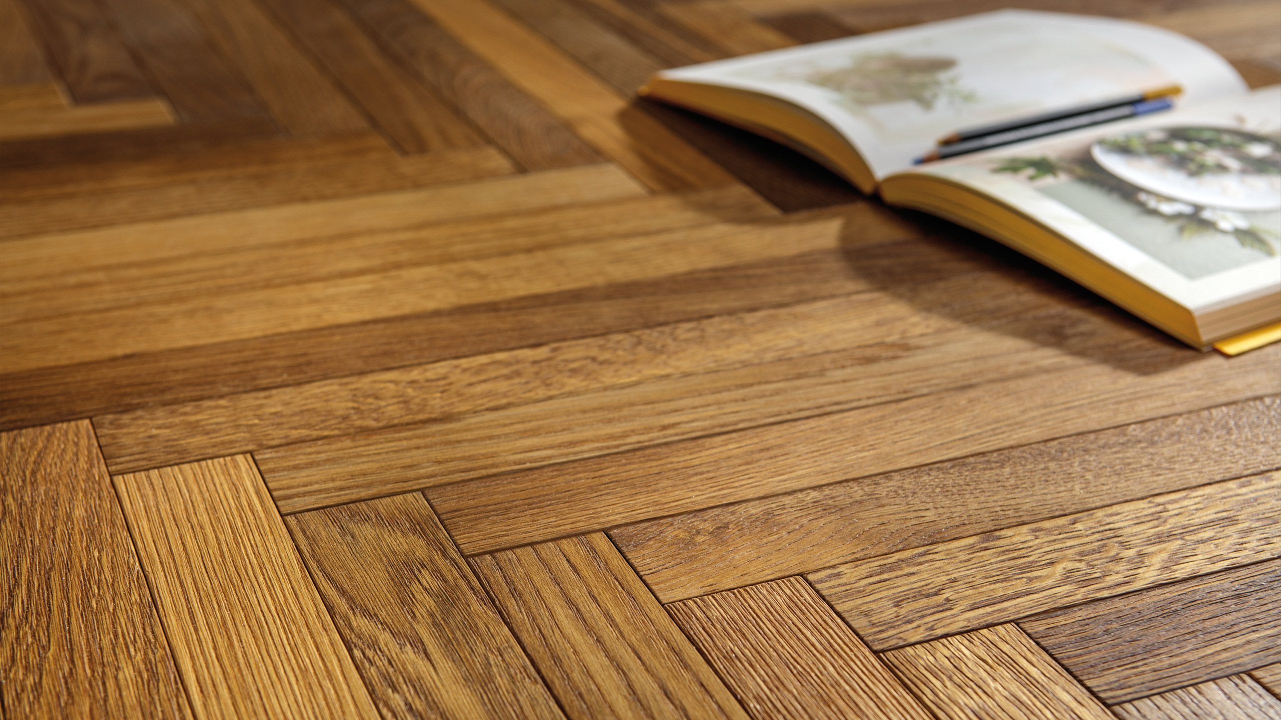 libro poggiato su pavimento parquet posato a spina di pesce