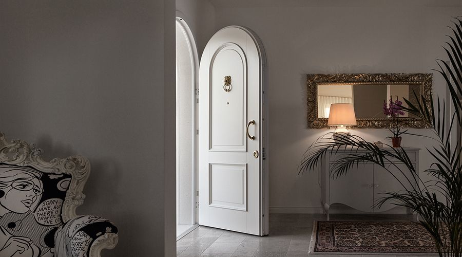 Portoncino blindato bianco con arco e dettagli dorati in ambiente classico ed elegante