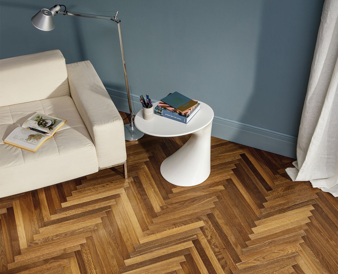 Pavimento in legno a spina di pesce in soggiorno moderno con pareti blu e arredi minimali
