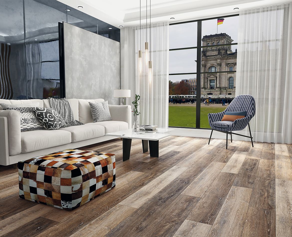Pavimento SPC effetto rovere in soggiorno moderno con grandi vetrate e divani bianchi.