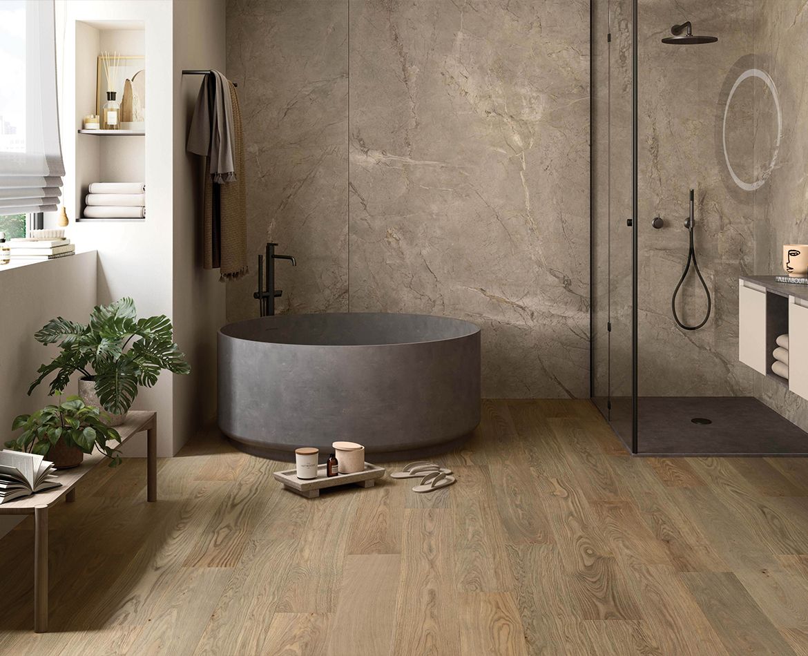 Pavimento in legno chiaro in bagno elegante con vasca freestanding e pareti effetto pietra