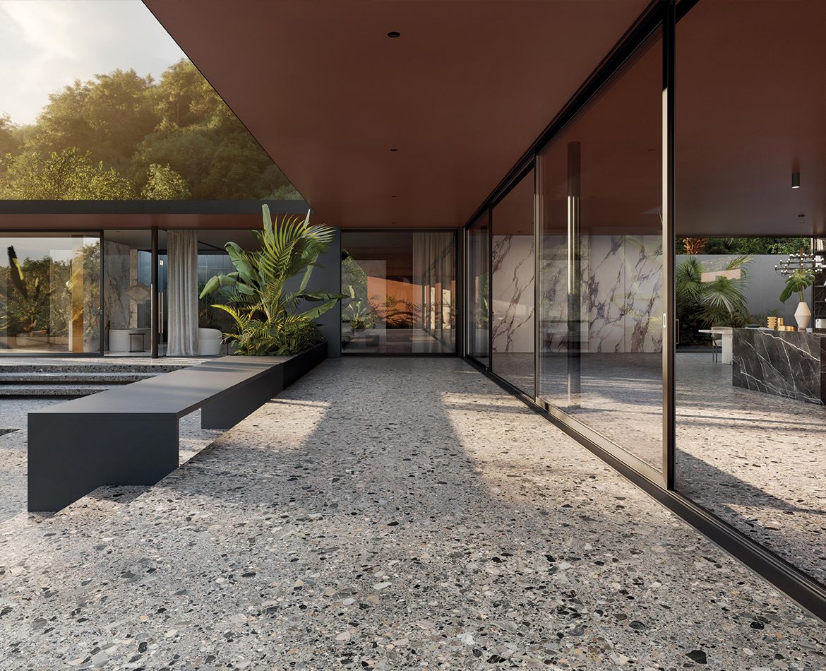 Spazio outdoor contemporaneo con grandi superfici vetrate e pavimento in grès effetto graniglia