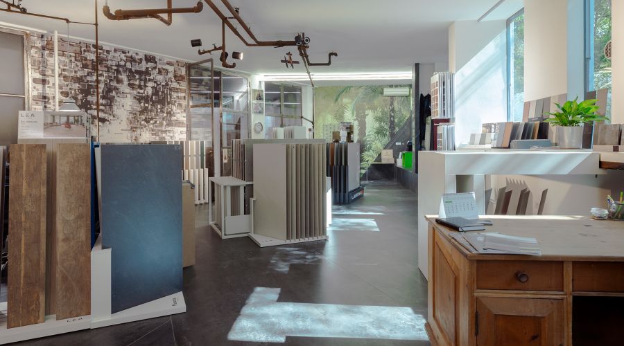 Panoramica luminosa dello showroom Ground con esposizione di piastrelle, legni e superfici decorative