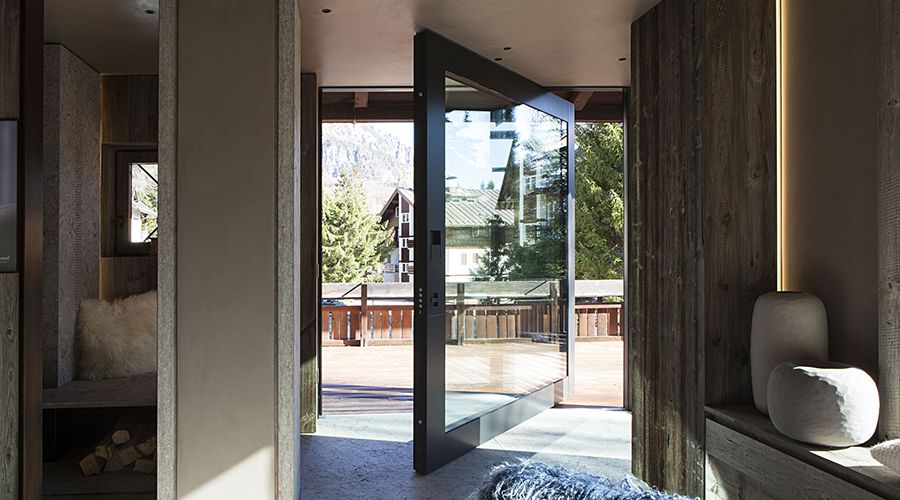 Portoncino blindato vetrato con telaio scuro in una casa di montagna dal design contemporaneo